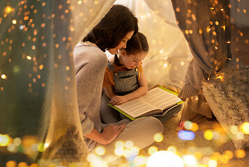 Image showing happy family reading book in kids tent at home