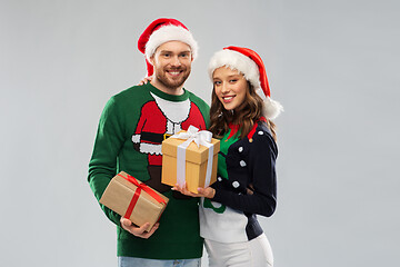 Image showing happy couple in christmas sweaters with gifts