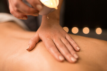 Image showing back massage with hot oil candle at spa