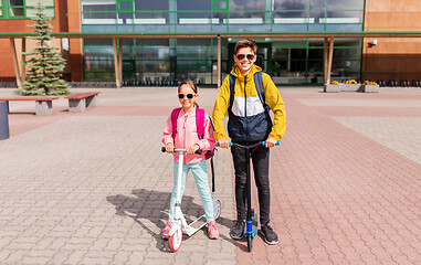 Image showing school children with backpacks riding scooters