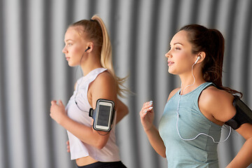 Image showing young women with earphones and smartphones running