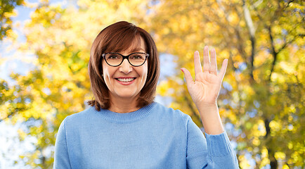Image showing portrait of senior woman in glasses waving hand