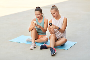 Image showing sporty women or friends with smartphone on rooftop