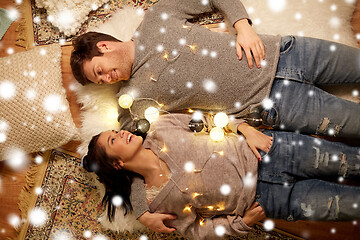 Image showing happy couple with garland lying on floor at home