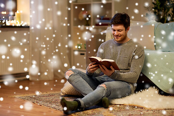 Image showing happy young man reading book at home