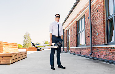 Image showing businessman with folding scooter on rooftop