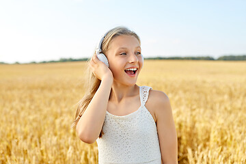 Image showing happy girl in headphones on cereal field in summer