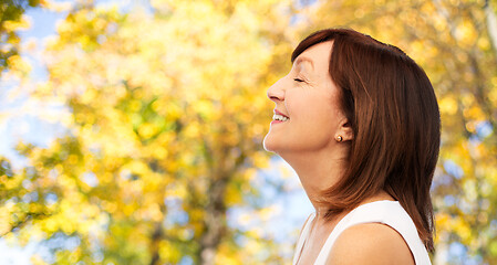 Image showing profile of smiling senior woman in autumn