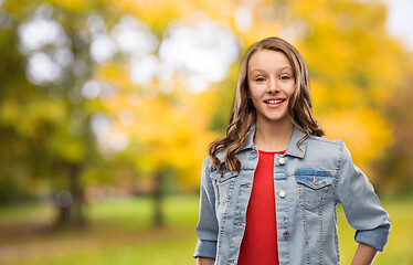 Image showing happy teenage girl in denim jacket in autumn park