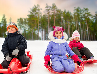 Image showing happy little kids sliding down on sleds in winter