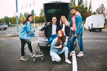 Image showing Group of four young diverse friends in jeanse outfit look carefree, young and happy on city\'s streets