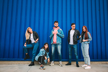 Image showing Group of four young diverse friends in jeanse outfit look carefree, young and happy on city\'s streets