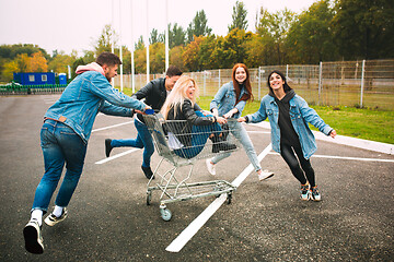 Image showing Group of four young diverse friends in jeanse outfit look carefree, young and happy on city\'s streets