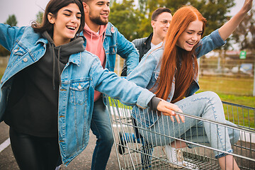 Image showing Group of four young diverse friends in jeanse outfit look carefree, young and happy on city\'s streets