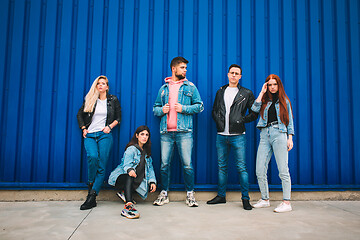 Image showing Group of four young diverse friends in jeanse outfit look carefree, young and happy on city\'s streets