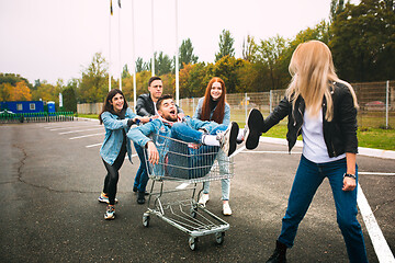 Image showing Group of four young diverse friends in jeanse outfit look carefree, young and happy on city\'s streets