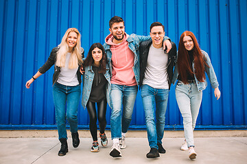 Image showing Group of four young diverse friends in jeanse outfit look carefree, young and happy on city\'s streets