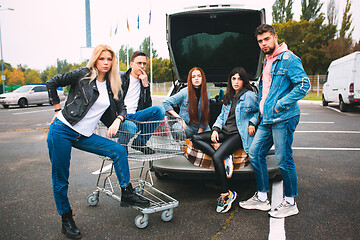 Image showing Group of four young diverse friends in jeanse outfit look carefree, young and happy on city\'s streets