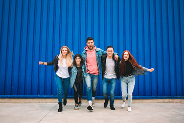 Image showing Group of four young diverse friends in jeanse outfit look carefree, young and happy on city\'s streets