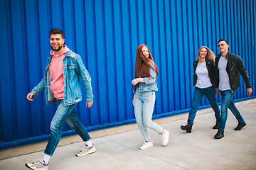 Image showing Group of four young diverse friends in jeanse outfit look carefree, young and happy on city\'s streets