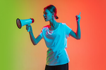 Image showing Young caucasian girl\'s portrait on gradient green-orange studio background in neon light