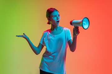 Image showing Young caucasian girl\'s portrait on gradient green-orange studio background in neon light