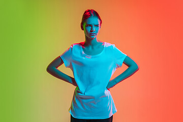 Image showing Young caucasian girl\'s portrait on gradient green-orange studio background in neon light