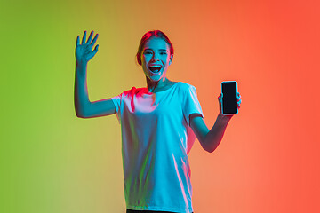 Image showing Young caucasian girl\'s portrait on gradient green-orange studio background in neon light