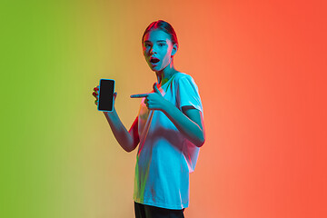 Image showing Young caucasian girl\'s portrait on gradient green-orange studio background in neon light