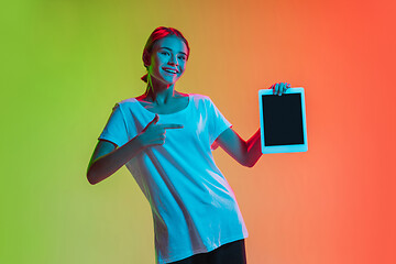 Image showing Young caucasian girl\'s portrait on gradient green-orange studio background in neon light