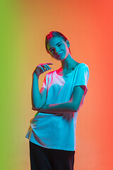 Image showing Young caucasian girl\'s portrait on gradient green-orange studio background in neon light