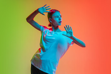 Image showing Young caucasian girl\'s portrait on gradient green-orange studio background in neon light