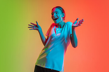 Image showing Young caucasian girl\'s portrait on gradient green-orange studio background in neon light