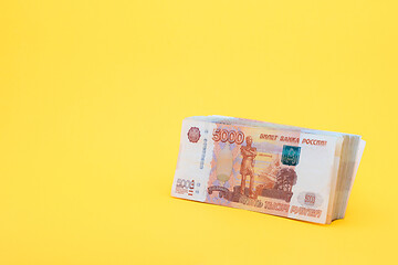 Image showing A pack of five thousandth bills on a yellow background