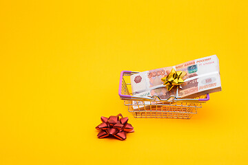 Image showing In the grocery basket is a bundle of five thousandth bills, next to it is a red bow