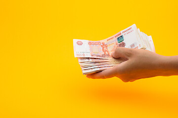 Image showing In hand a pack of five thousandth Russian rubles, yellow background