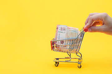 Image showing Hand carries a grocery cart with a pack of five thousandth Russian rubles