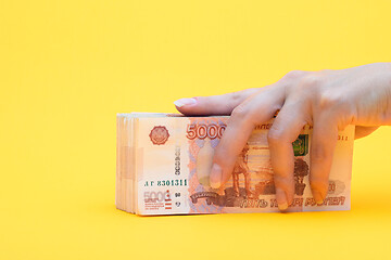 Image showing Hand covered a pack of five thousandth bills, yellow background