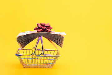 Image showing On the handles of the grocery cart lies a bundle of notes packed with gift ribbon and a red bow