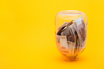 Image showing In an upturned glass jar are five thousandth bills