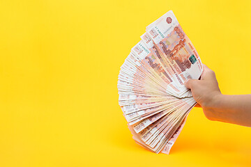 Image showing Hand holds a fan from a pack of five thousandth Russian bills on a yellow background