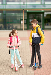 Image showing happy school children with backpacks and scooters