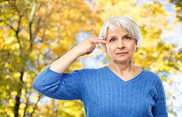 Image showing old woman making finger gun gesture in autumn park