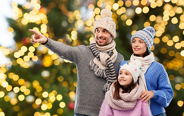 Image showing happy family in winter hats over christmas lights