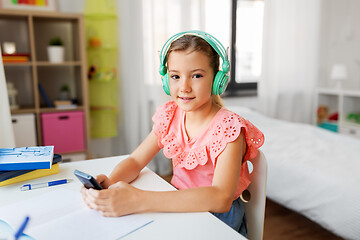 Image showing girl in headphones listening to music on cellphone