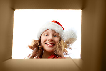 Image showing girl in santa hat looking into christmas gift box