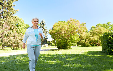 Image showing senior woman running along summer park