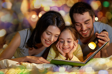 Image showing happy family reading book in bed at night at home