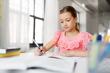 Image showing student girl with book writing to notebook at home