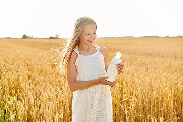 Image showing happy girl with bottle of milk on cereal field